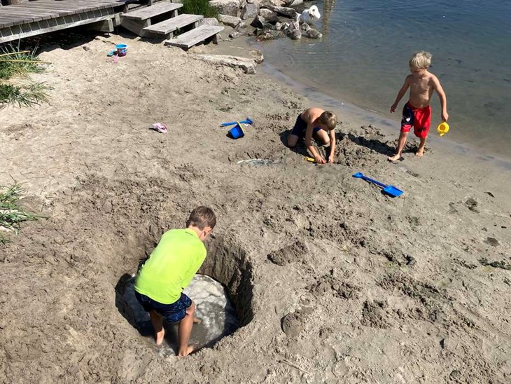 Victor graver en pool i strandkanten. 