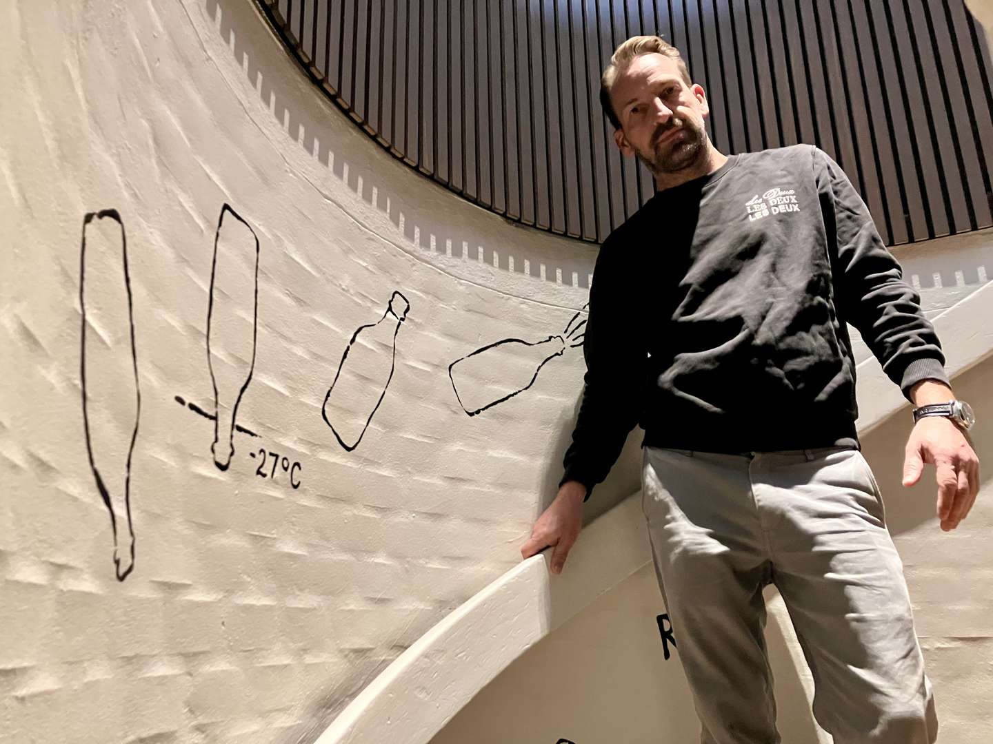 Casper J. Johansen på trappen til kælderen, som er prydet af relevant vægkunst.