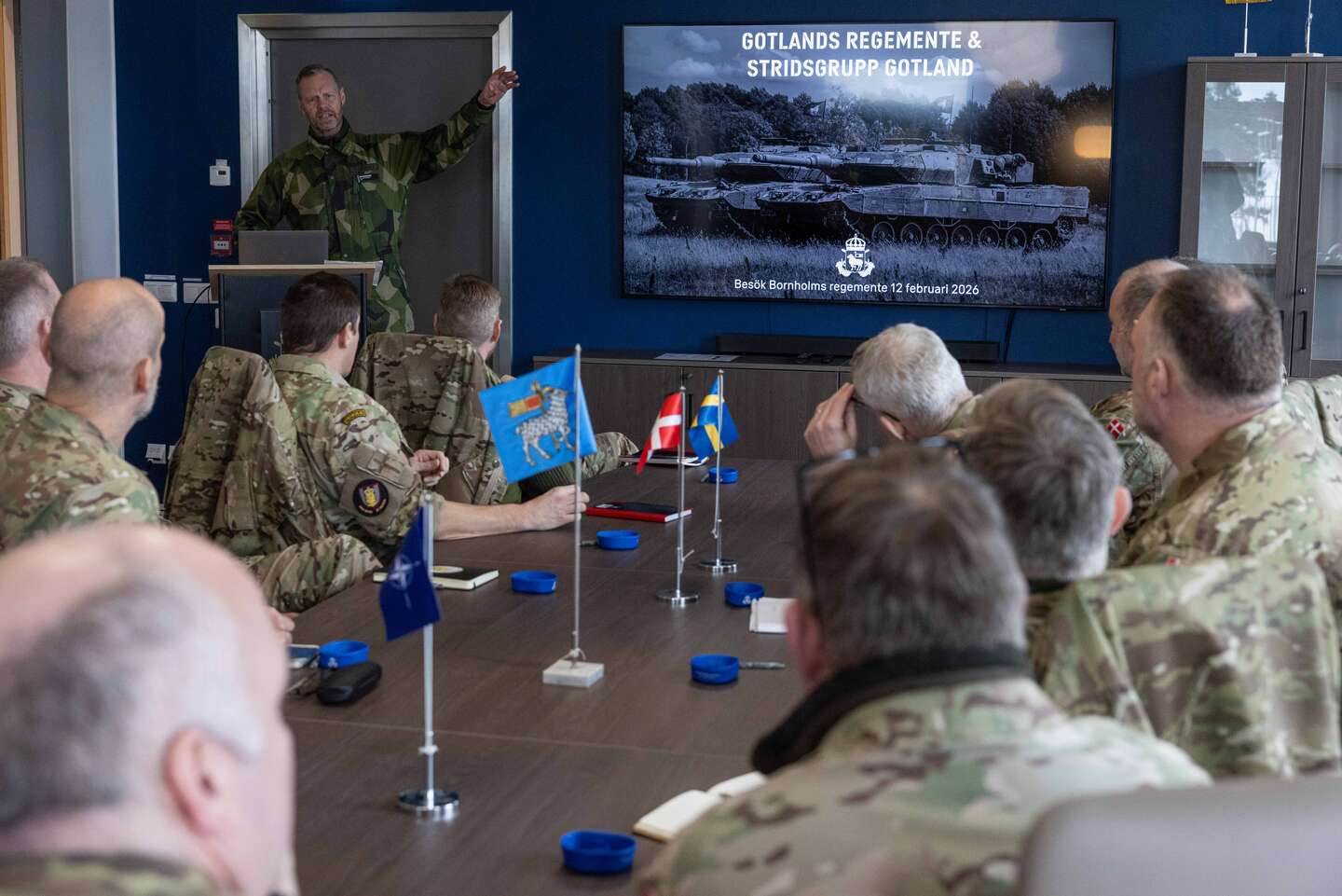 På bordet ses Sveriges og Danmarks flag ved siden af Gotlands årdhundreder gamle flag med en blå baggrund og en vædder i sølv med guldbeklædte horn samt Natos marineblå flag. Foto: Daniel Klintholm/Försvarsmakten.